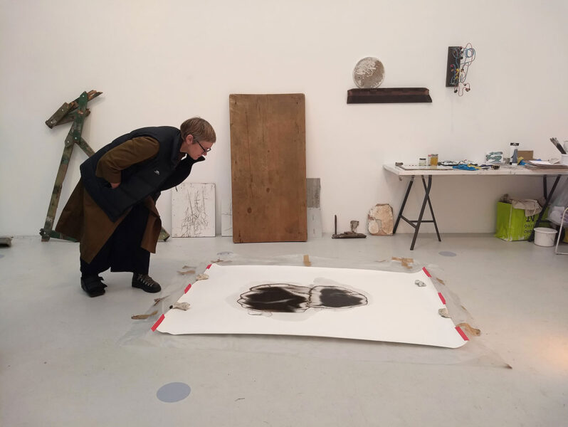 Incubator of ideas – Sam Hodge examining a work in progress with various pieces by Marcia Teusink behind her